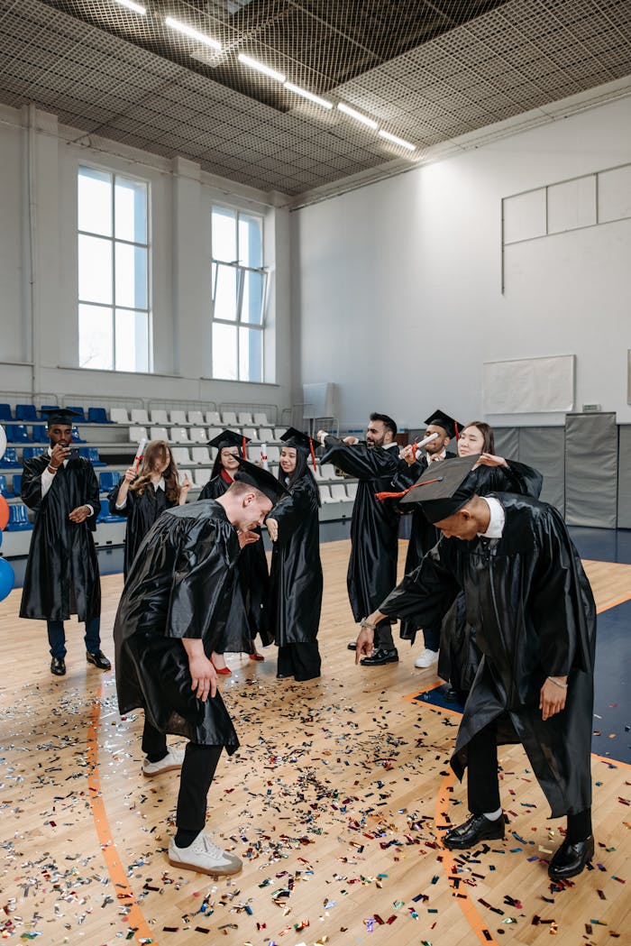 The Art of Drawing Readers In: Your attractive post title goes here Graduates celebrating with confetti in a bright gymnasium. Diverse group in gowns and caps.